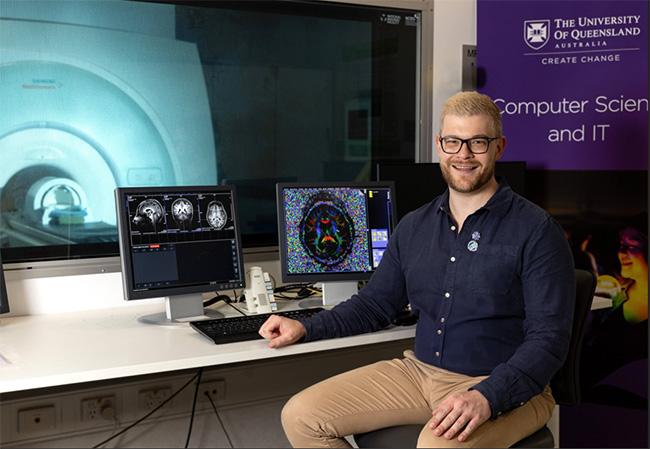Dr Thomas Shaw using software in front of an MRI machine.